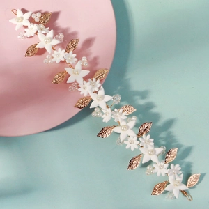 Detailed close-up of golden leaf headband with white ceramic flowers and faux pearls