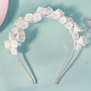 Détail de fleurs en tissu blanc avec perles sur un serre-tête doré pour mariages