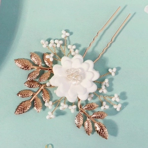 Detail of handmade white flower and pearl bridal hair pin with golden leaves
