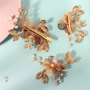 Détail de barrettes à fleurs en fil doré avec perles et strass faits à la main