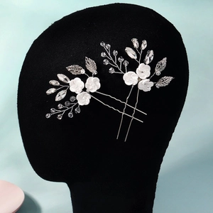 Detail of silver wedding hair pins with white ceramic flowers and sparkling crystals