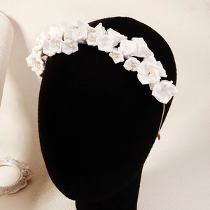 Détail d'un élégant serre-tête floral blanc avec perles sur base dorée pour mariée