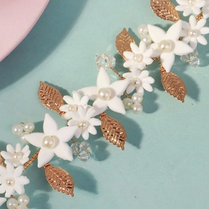 Macro view of gold leaf bridal headband with white matte petals and pearls