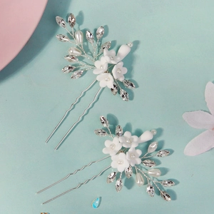 Close-up of handmade white clay flower hair pins with pearls and crystals for brides