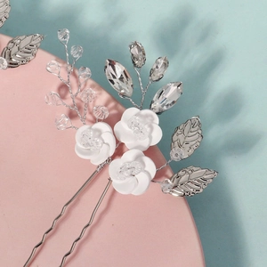 Close-up of handmade ceramic flower hair pin with silver leaves and crystal beads