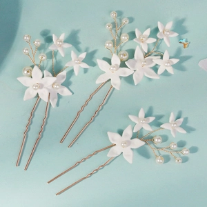 Detail of three-piece bridal hair pins with white clay flowers and pearls on gold wire