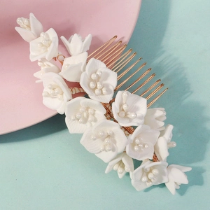 Détail d'un peigne à cheveux de mariée avec fleurs blanches, perles et fil doré
