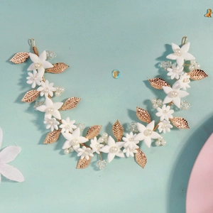 Close-up of golden leaf headband with white ceramic flowers, pearls and crystal beads