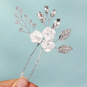 Detail of white ceramic flowers and crystal beads on a silver wedding hair pin