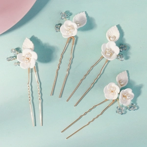 Detail of handmade white clay flower hair pins with pearls and blue beads on gold metal