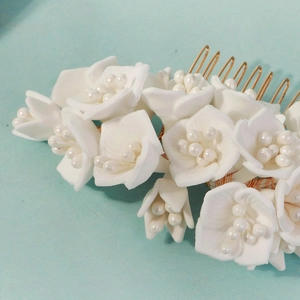 Gros plan détaillé des pétales de fleurs 3D avec perles sur un peigne de mariée doré