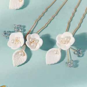 Detail of handmade bridal hair pins with white clay flowers and pearls on golden wave stems