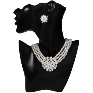 Detail of four-layer pearl necklace and flower earrings on a black mannequin display