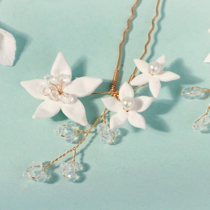 Detailed macro view of handmade clay flower hair pin with pearls and gold wire design