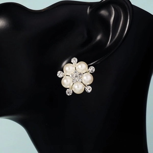 Macro view of elegant flower-shaped pearl earrings with crystal accents on a model
