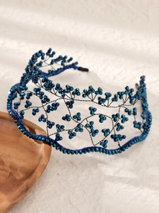 Detail of handcrafted blue beaded headband with intricate wire structure on wooden tray