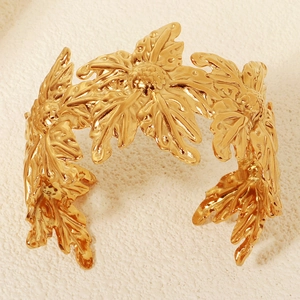 Makroaufnahme einer goldenen breiten Armspange mit floralen und Blattreliefmustern