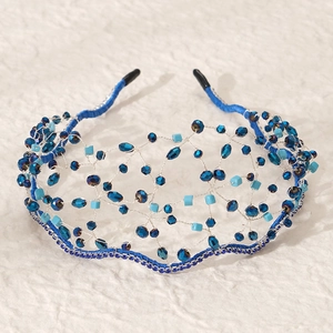 Gros plan d'un serre-tête de mariée artisanal avec cristaux bleus et fil d'argent tissé