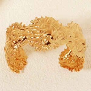 Nahaufnahme des goldenen breiten Armreifs mit detaillierten Löwenkopf-Reliefgravuren