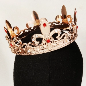 Detail of a vintage gold crown with red gems and fleur-de-lis on a black mannequin