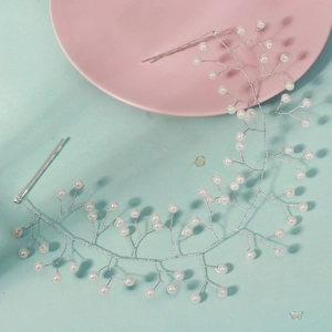 Handmade bridal hair vine with white pearls and silver wire on light blue background