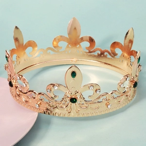 Close-up of golden baroque crown featuring green emerald gems and intricate fleur-de-lis