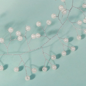 Macro shot of handmade silver wire hair vine with white pearls for bridal styling