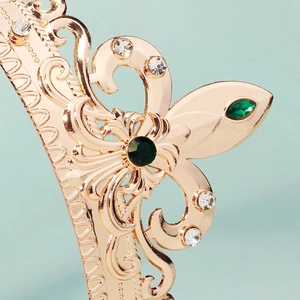 Detail of rose gold crown with emerald rhinestones and baroque hollow filigree patterns