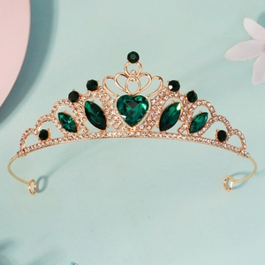 Detailed close-up of golden princess crown featuring emerald heart-shaped gemstones