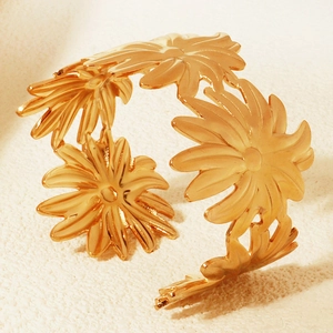 Detailaufnahme eines goldenen Armreifs mit hohlem Gänseblümchen-Muster und Glanz