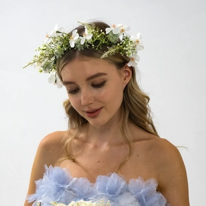 Gros plan d'une couronne de fleurs blanches et feuilles vertes pour coiffure de mariée