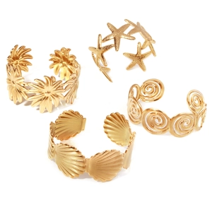 Set aus 4 vergoldeten Armreifen mit Motiven von Sonnenblumen, Seesternen, Muscheln und Spiralen