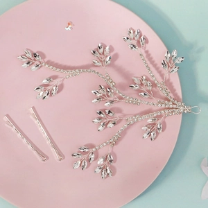 Macro detail of silver rhinestone leaf bridal hairpiece with matching hair pins on a tray