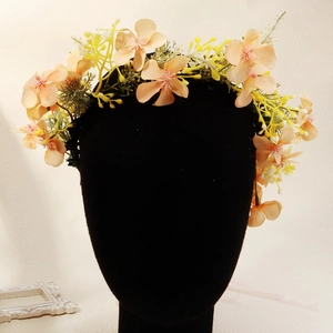 Vue détaillée d'une couronne de fleurs bohème avec fleurs rose abricot et feuilles vertes