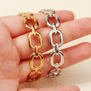 Dettaglio dei bracciali a catena spessa in oro e argento al polso con finitura lucida