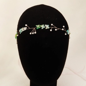 Detail of bridal headband with light green resin petals and white pearls on gold wire
