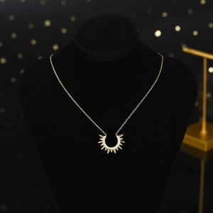 Makroaufnahme eines goldenen Sonnenanhängers mit Zirkon-Besatz auf schwarzem Display