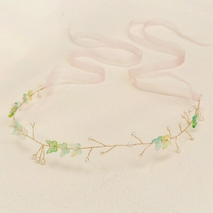 Close-up of handmade bridal headband with gold wires, white pearls and pink ribbons