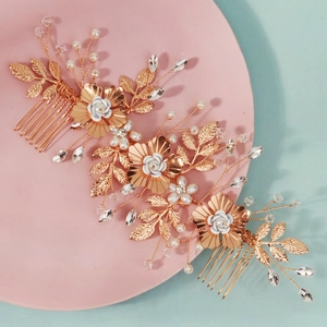 Close-up of golden handmade bridal hair comb with white flowers, pearls and rhinestones