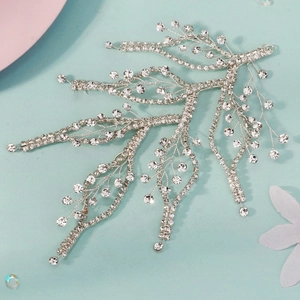 Détail d'un accessoire cheveux en forme de branche argentée avec strass pour mariées