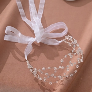 Détail de bandeau de mariée artisanal en maille de cristal avec ruban de soie blanc