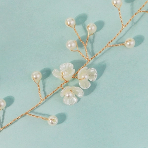 Détail du bandeau de mariée fait main avec fil doré, perles blanches et fleurs délicates