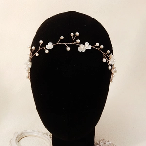 Détail d'un bandeau de mariée avec fil doré, fleurs en résine blanche et fausses perles
