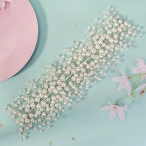 Elegant bridal hairband with white pearls and silver wire on light green background