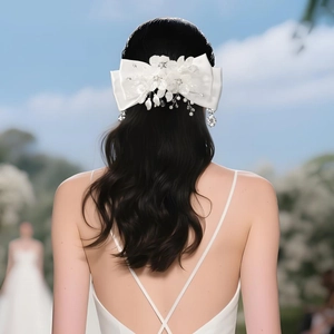 Detail of a large white bridal bow hair clip with handmade fabric flowers and pearls