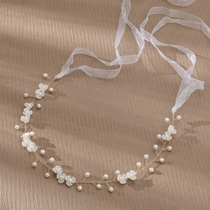 Détail d'un bandeau de mariée avec fleurs blanches, perles et rubans en organza fin