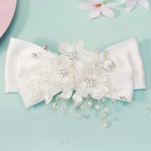 Detail of a large white satin bridal hair clip with handcrafted 3D flowers and pearls