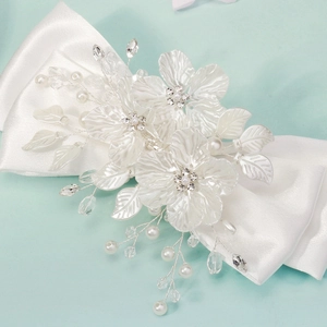 Detail of white bridal hair clip with handmade 3D flowers, pearls and satin bow