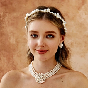 Detail of elegant bridal jewelry set with triple-layer pearl necklace and matching headband