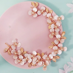 Detalle de diadema nupcial con flores de metal rosa con perlas blancas y hojas doradas